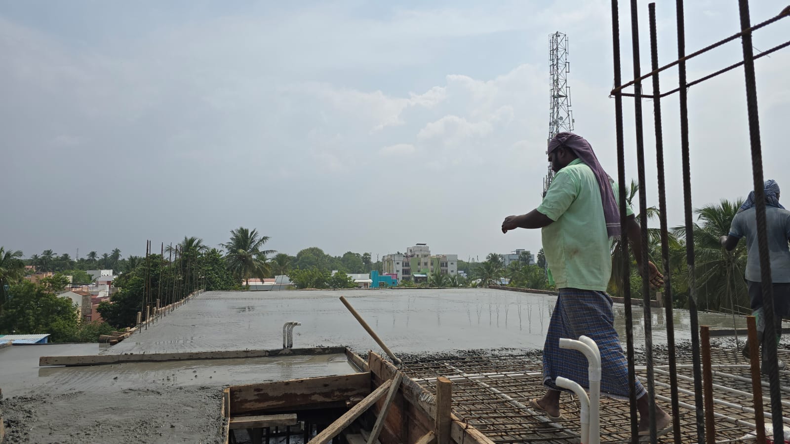 Workers carrying out roof slab work at the Tirunelveli residential flats site